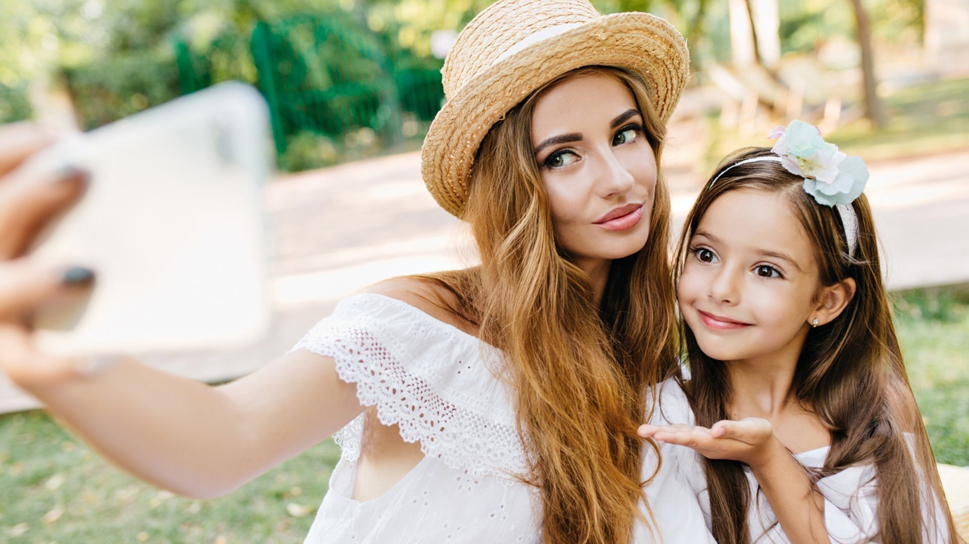 Mother and daughter taking a selfie together in the park on a sunny day