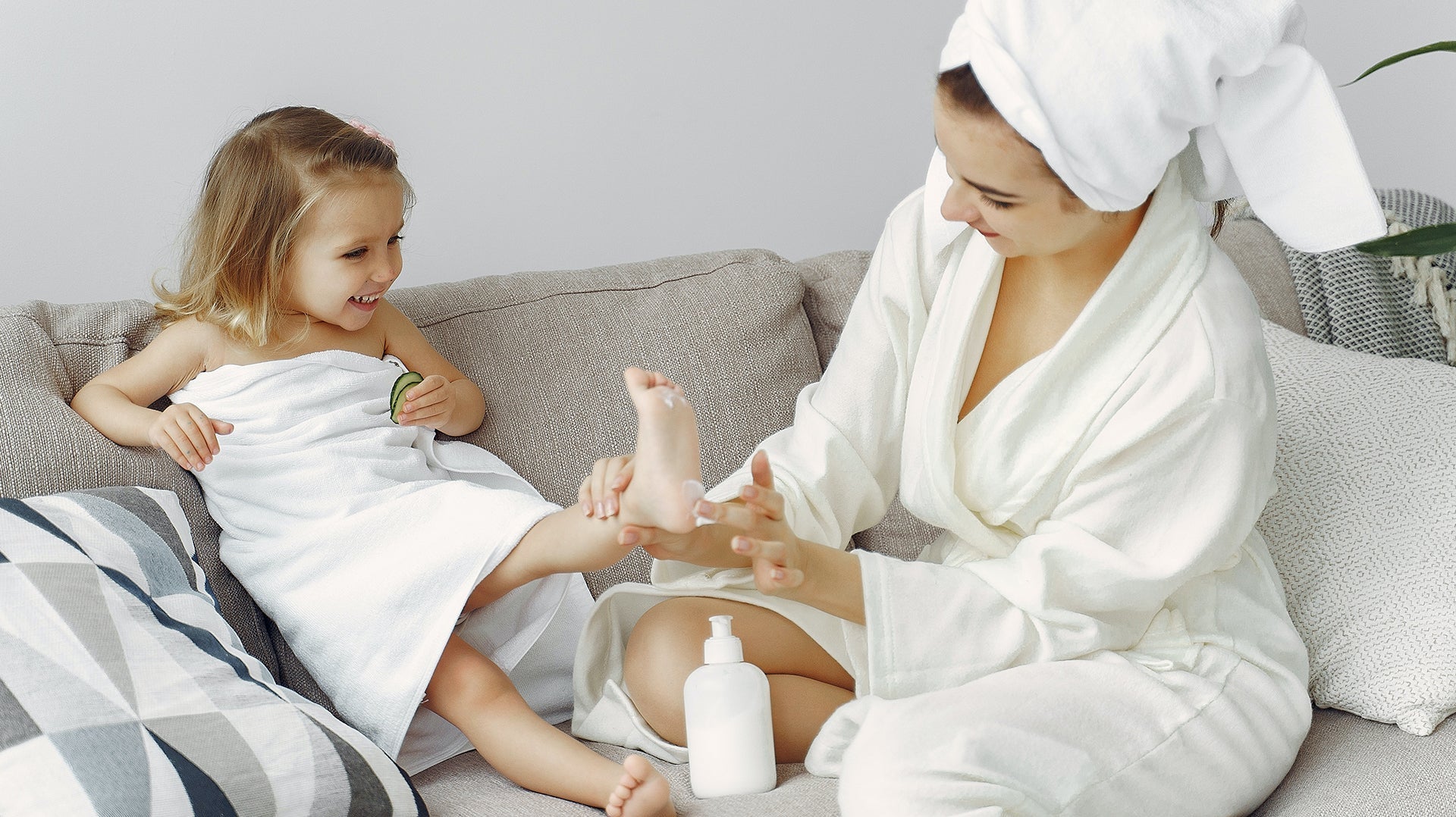 Mom and daughter enjoying skincare routine at home with lotion after bath.