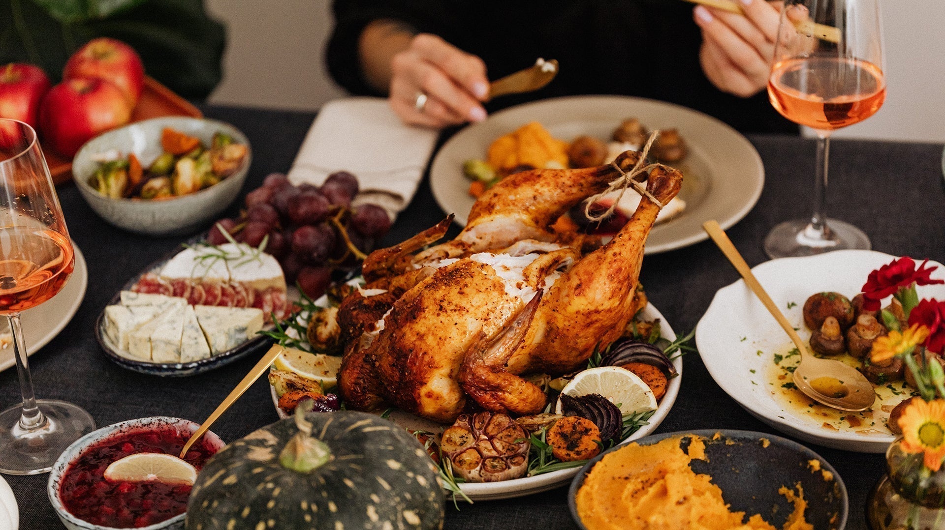 Holiday dinner table with roasted chicken, vegetables, pumpkin, cheese, and festive side dishes.