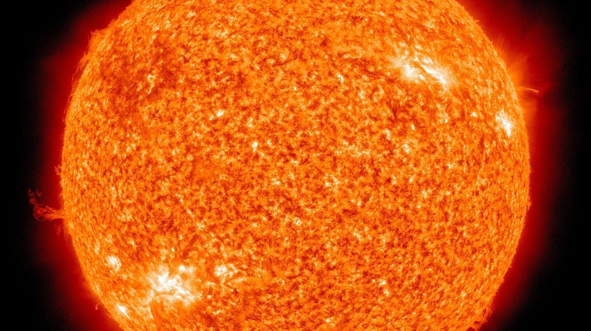 High-resolution close-up of the Sun with visible solar flares and fiery orange surface texture.