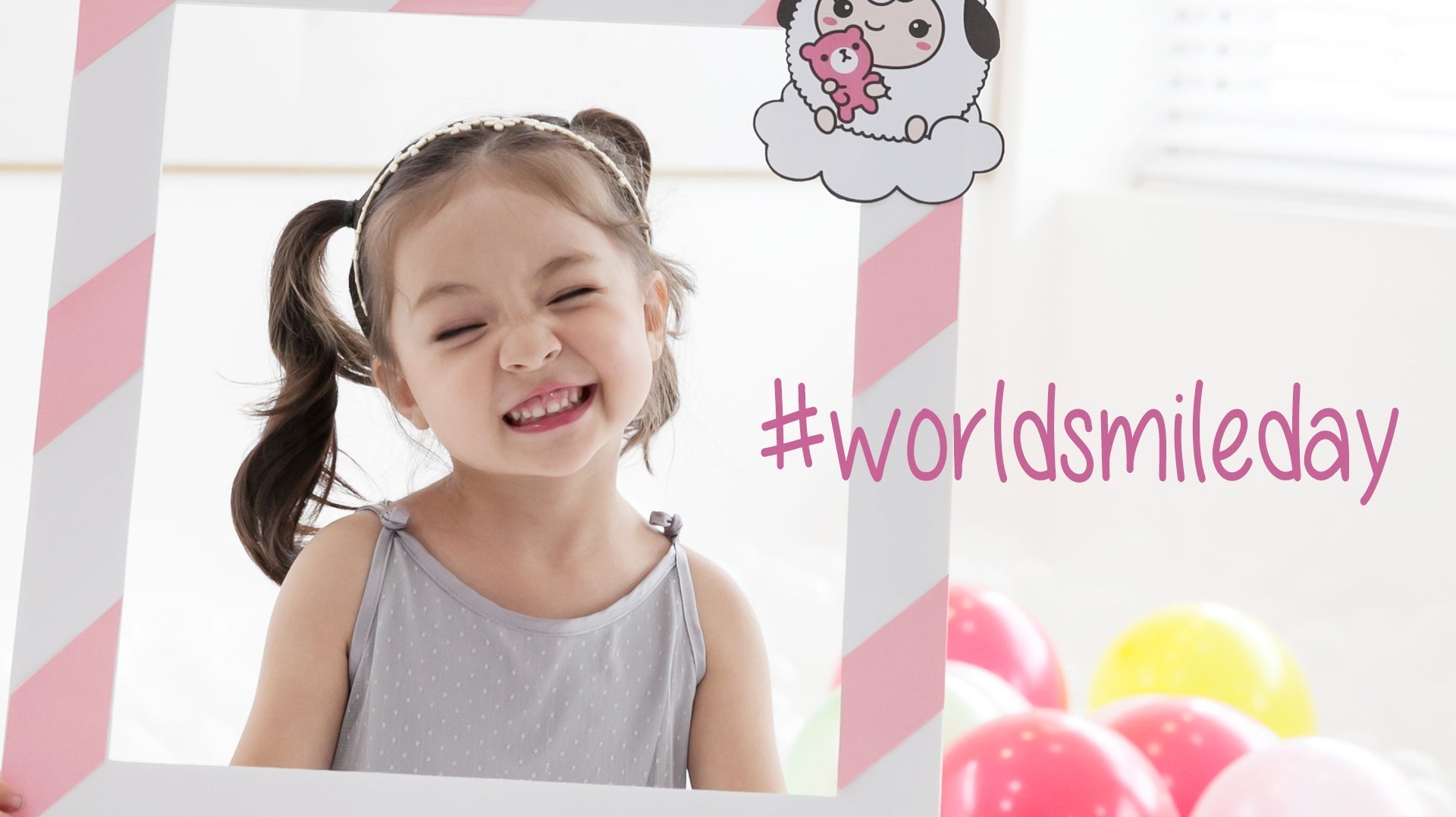 Happy child celebrating World Smile Day posing with a themed photo frame.