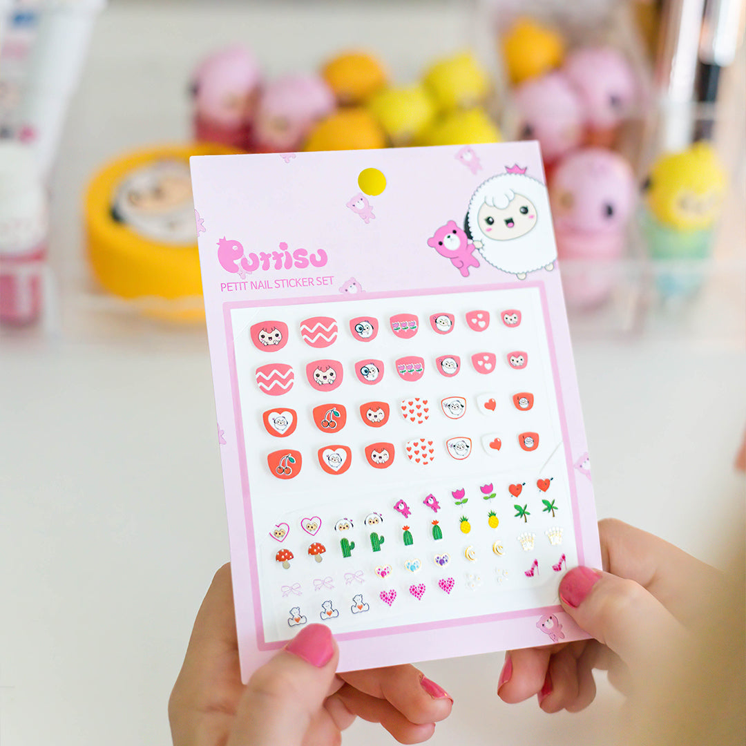 A woman holding a sheet of pink nail stickers with cartoon designs.