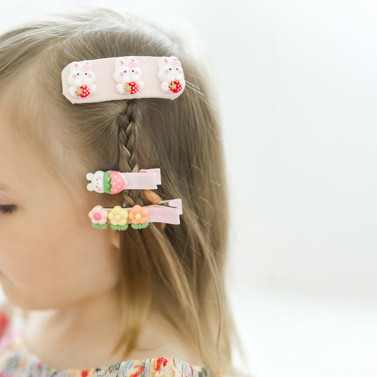 Children's hair clips with bunny and flower designs on a blurred background