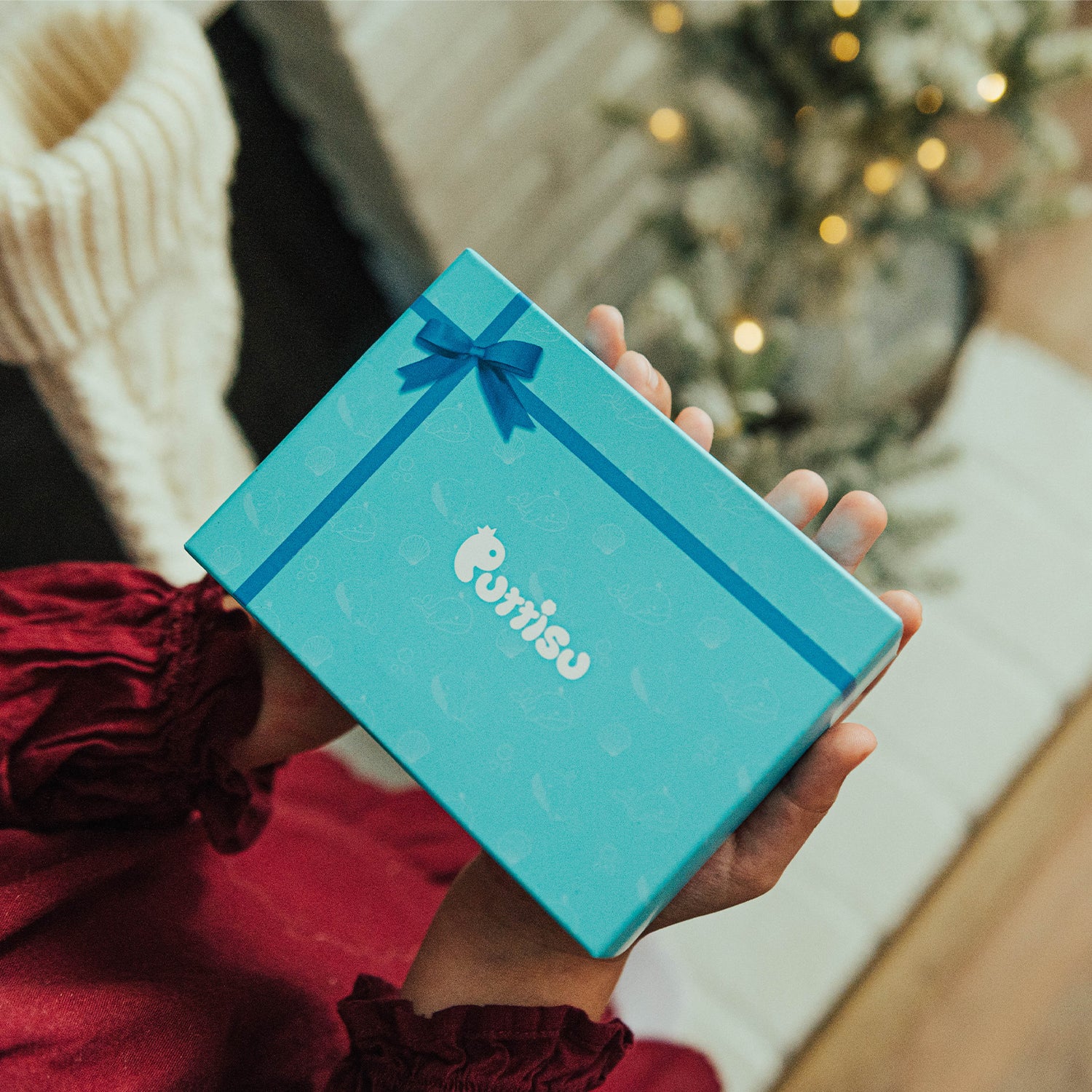 A person holding a light blue gift box with a bow.