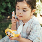 Young girl applying face powder outdoors.