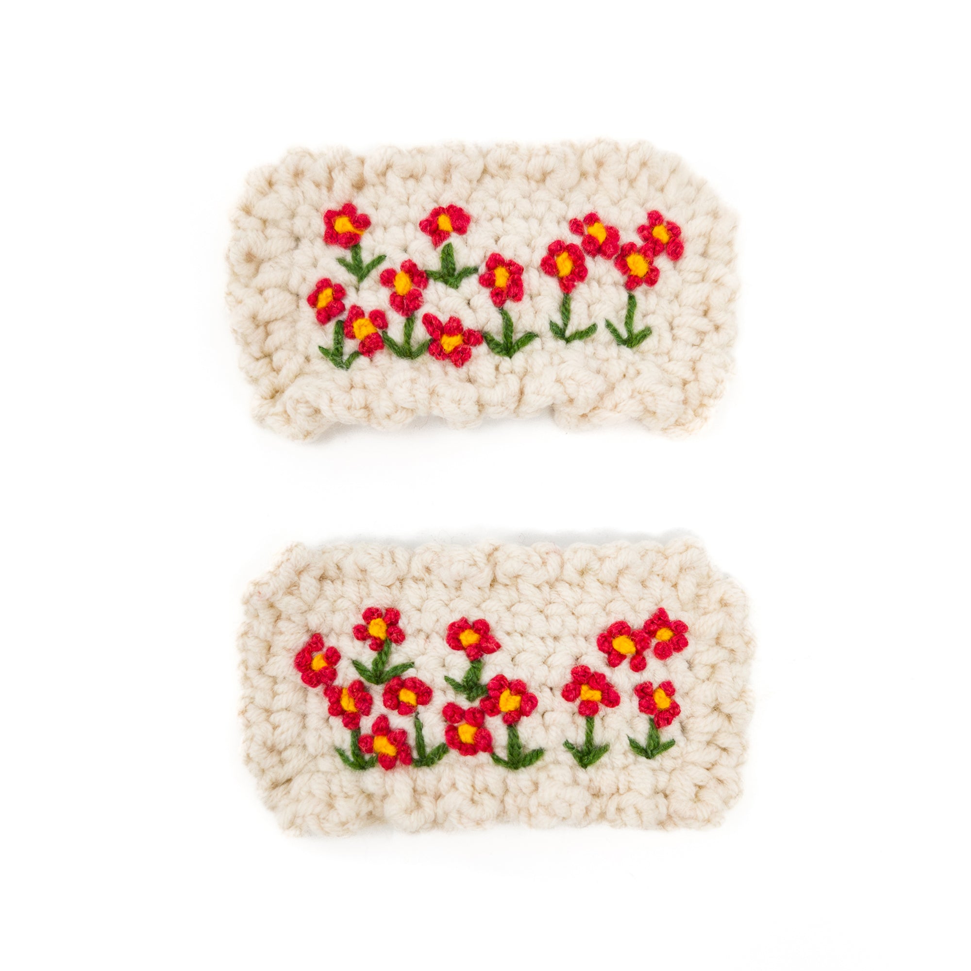 Two crocheted wrist warmers with embroidered red and yellow flowers.