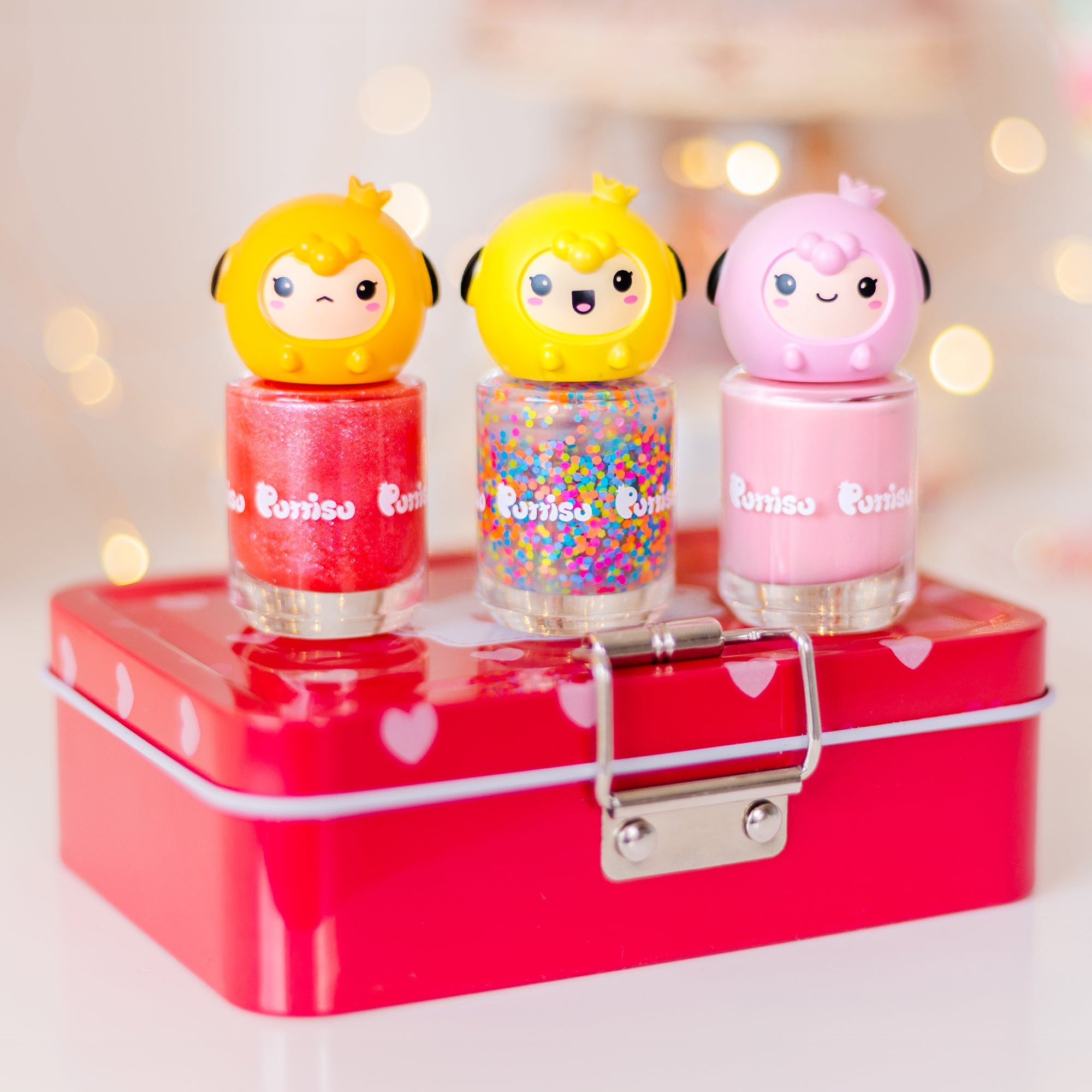 Three colorful nail polish bottles with cartoon sheep cap on a red heart-patterned box.