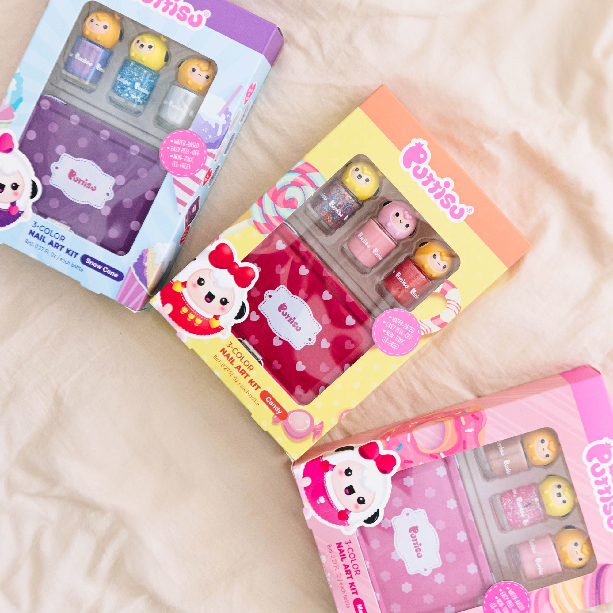 Three colorful Purriso nail art kits on a beige surface.