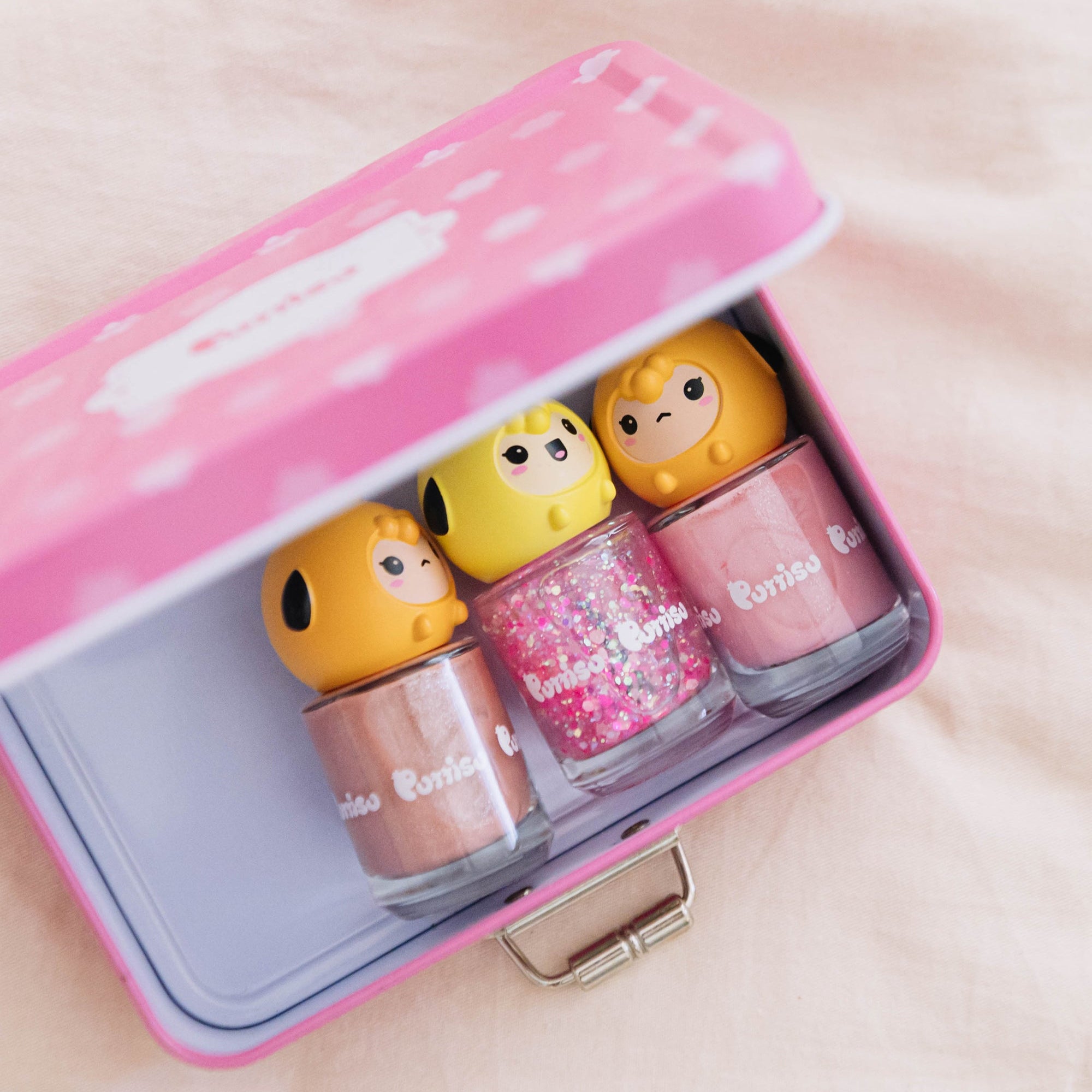 Pink metal box filled with colorful nail polish bottles with cartoon character tops.