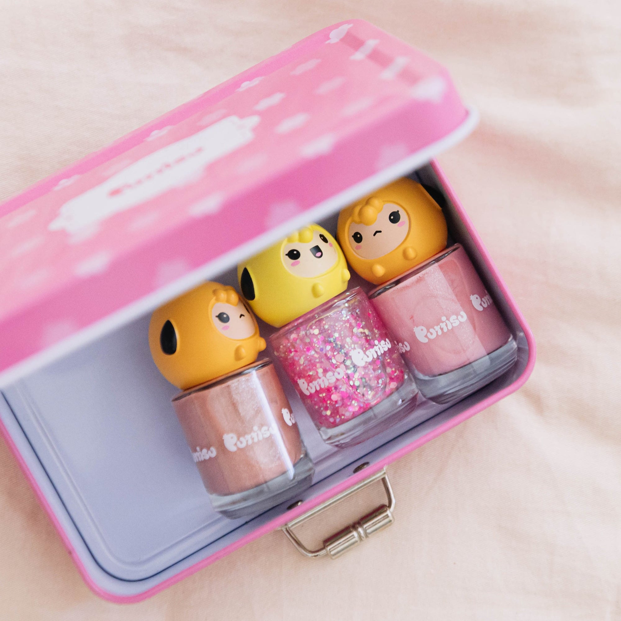 Three bottles of Pomisu nail polish in a pink suitcase.