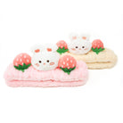 Two fluffy headbands with bunny and strawberry decorations, pink and beige.