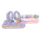 Two fuzzy headbands: a purple headband with bunny ears and a strawberry accessory, and a pink headband with pastel-colored heart accessories.