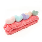 Pink plush headband with pastel heart decorations.