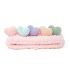 Pink plush headband with five heart-shaped decorations.