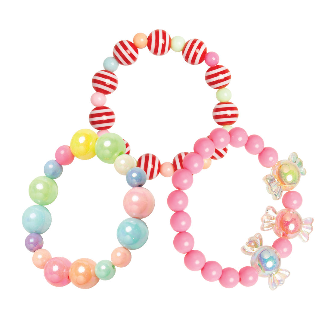 Three beaded bracelets. One bracelet is composed of red and white striped beads, interspersed with pink, orange, and green beads. Another bracelet has large beads in pastel colors. The last bracelet is solid pink, with transparent candy charms.