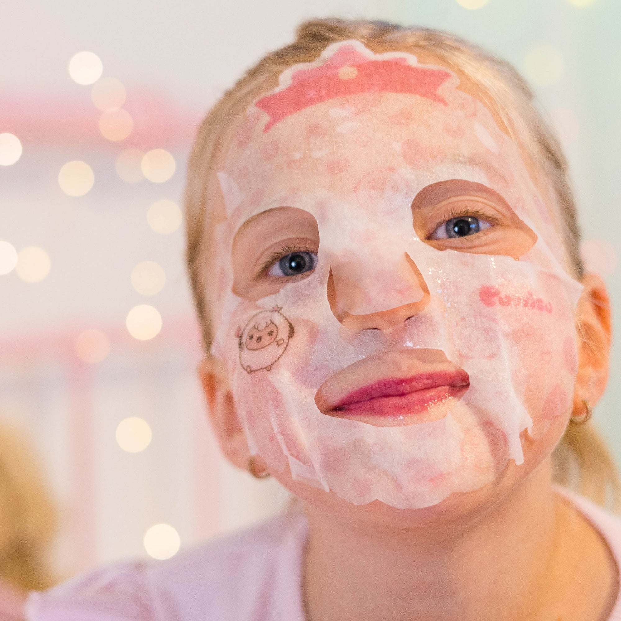 Young girl with face mask, pink shirt, and bokeh lights in background.