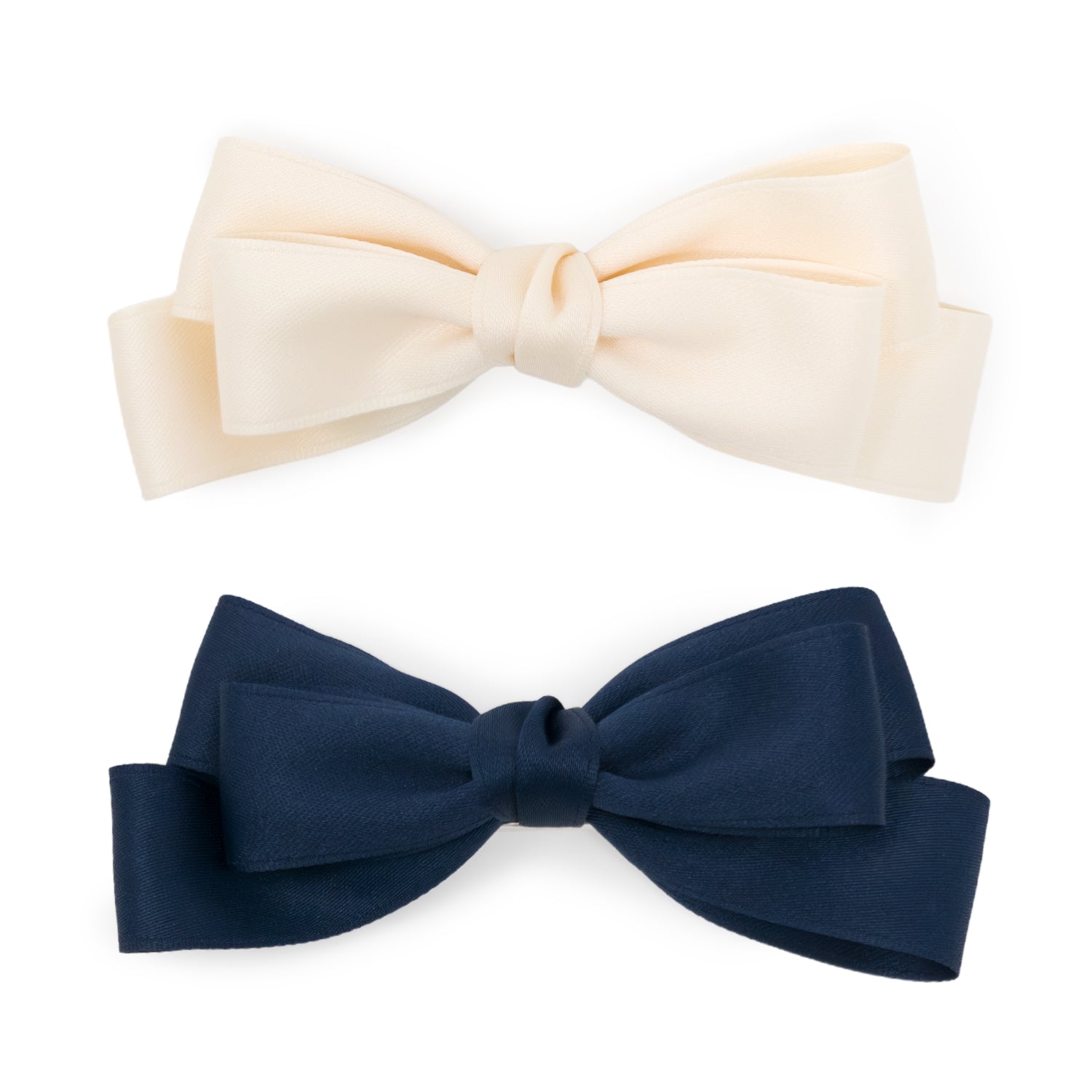 Top-down view of two large satin double bow clips, one cream and one navy blue.