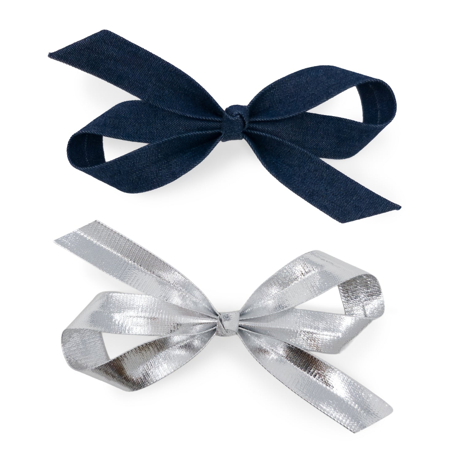 A set of two bow clips: one dark blue denim with visible weave and one shiny silver metallic with a crinkled texture, both seen from above.
