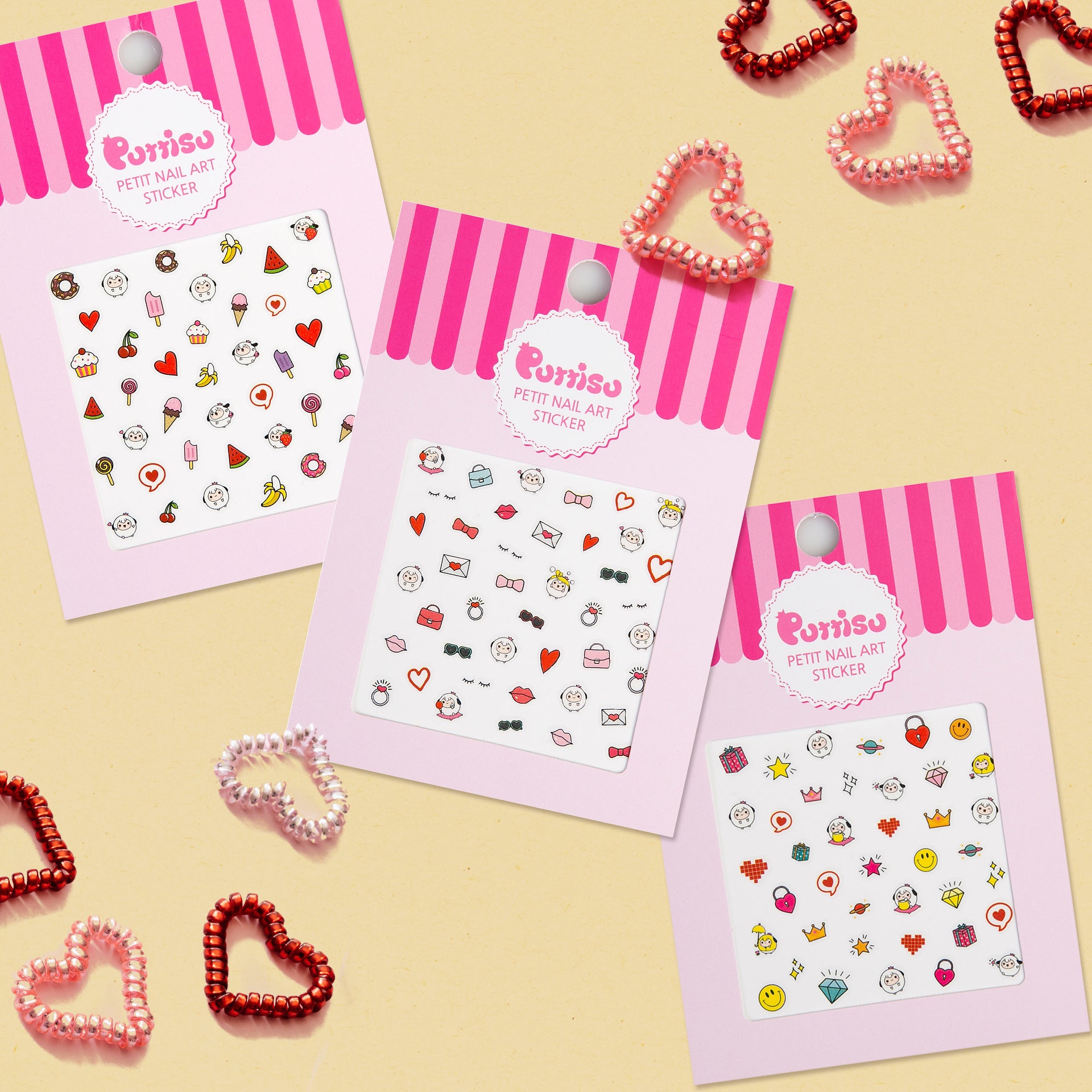 Three sheets of nail art stickers with pink and white packaging, scattered with heart-shaped hair ties.