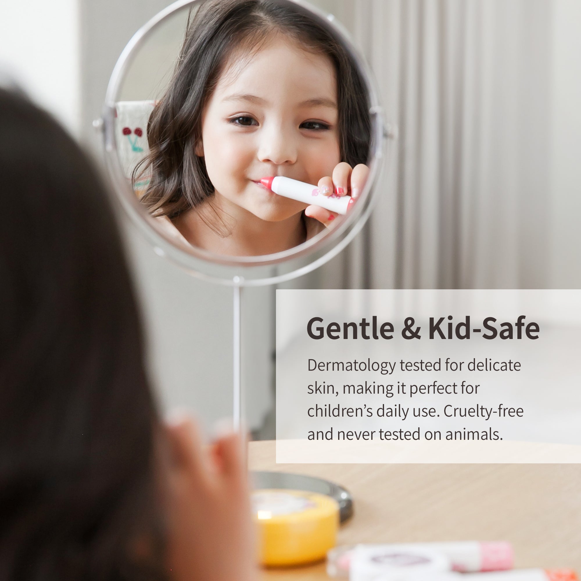 A young child applying lip balm while looking in the mirror.