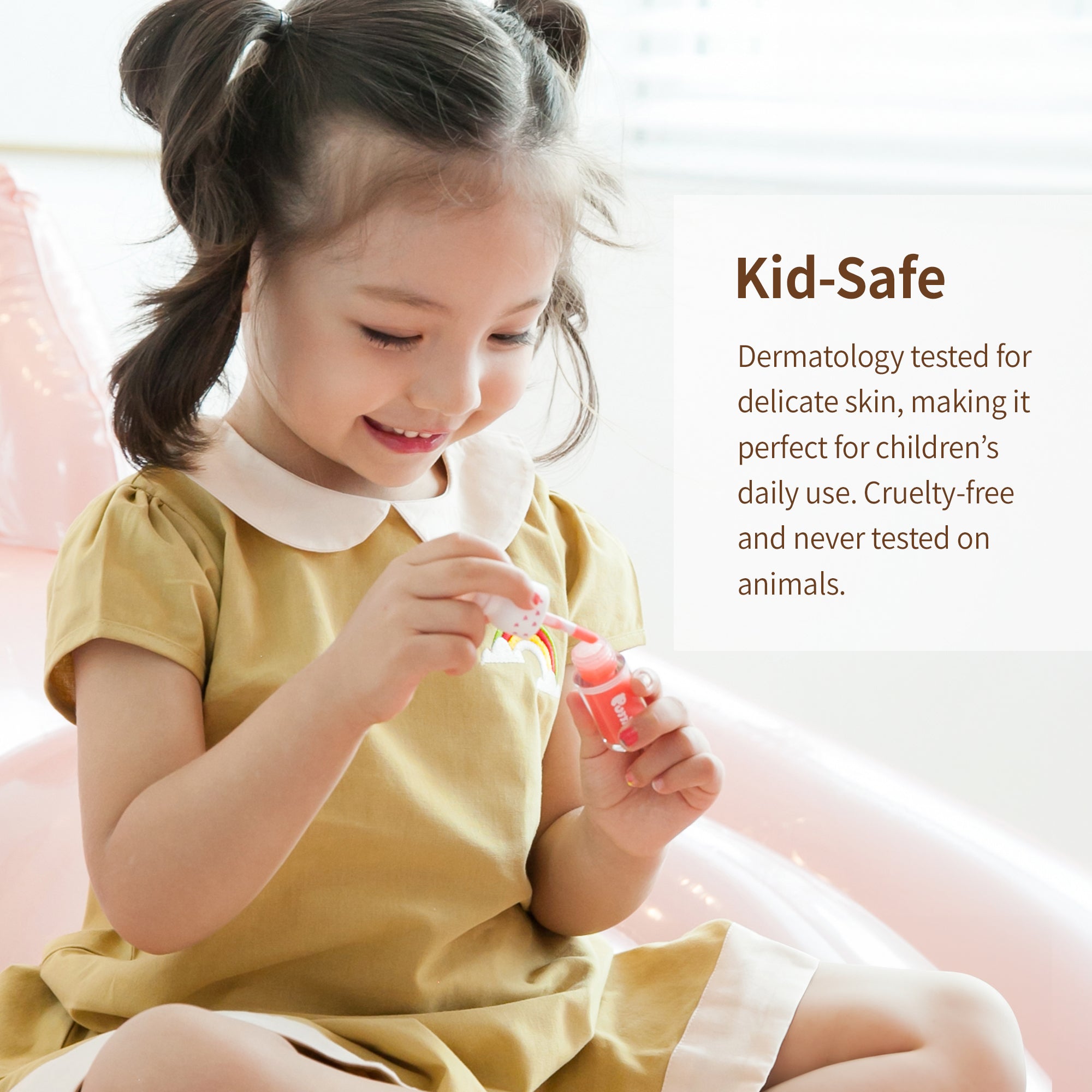 A smiling child in a yellow dress sits on a pink surface, painting her nails with a red bottle of nail polish. Text in a white box to the right reads "Kid-Safe."
