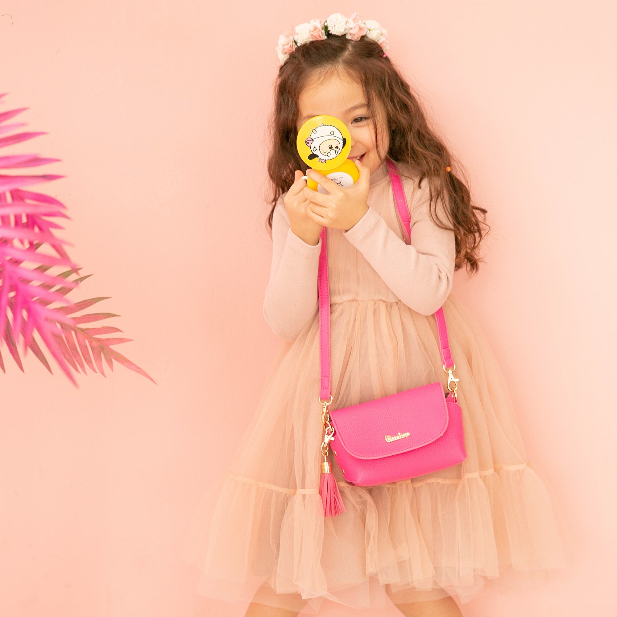 Girl in dress with pink purse holds yellow mirror.
