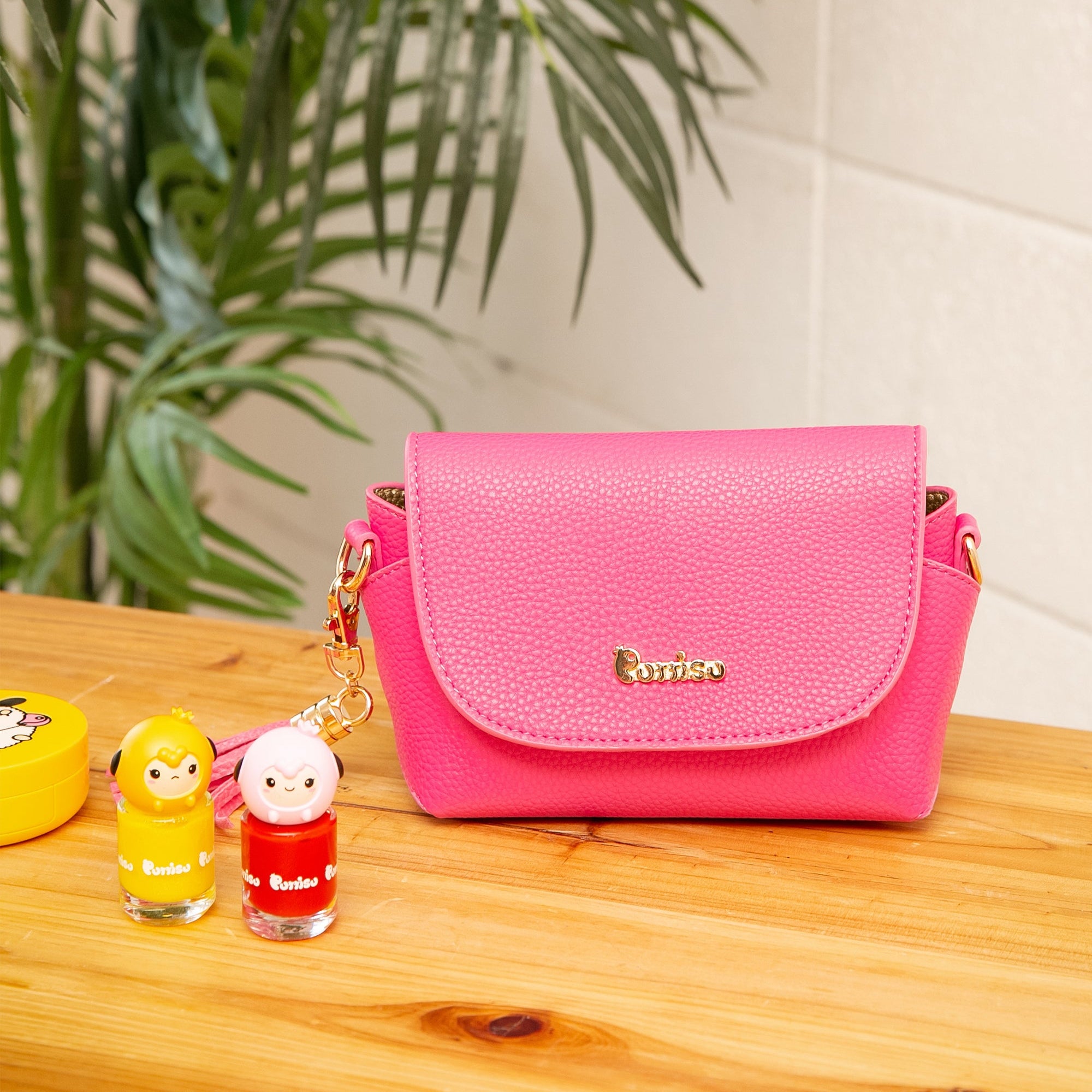 A pink purse next to yellow and pink nail polish bottles.