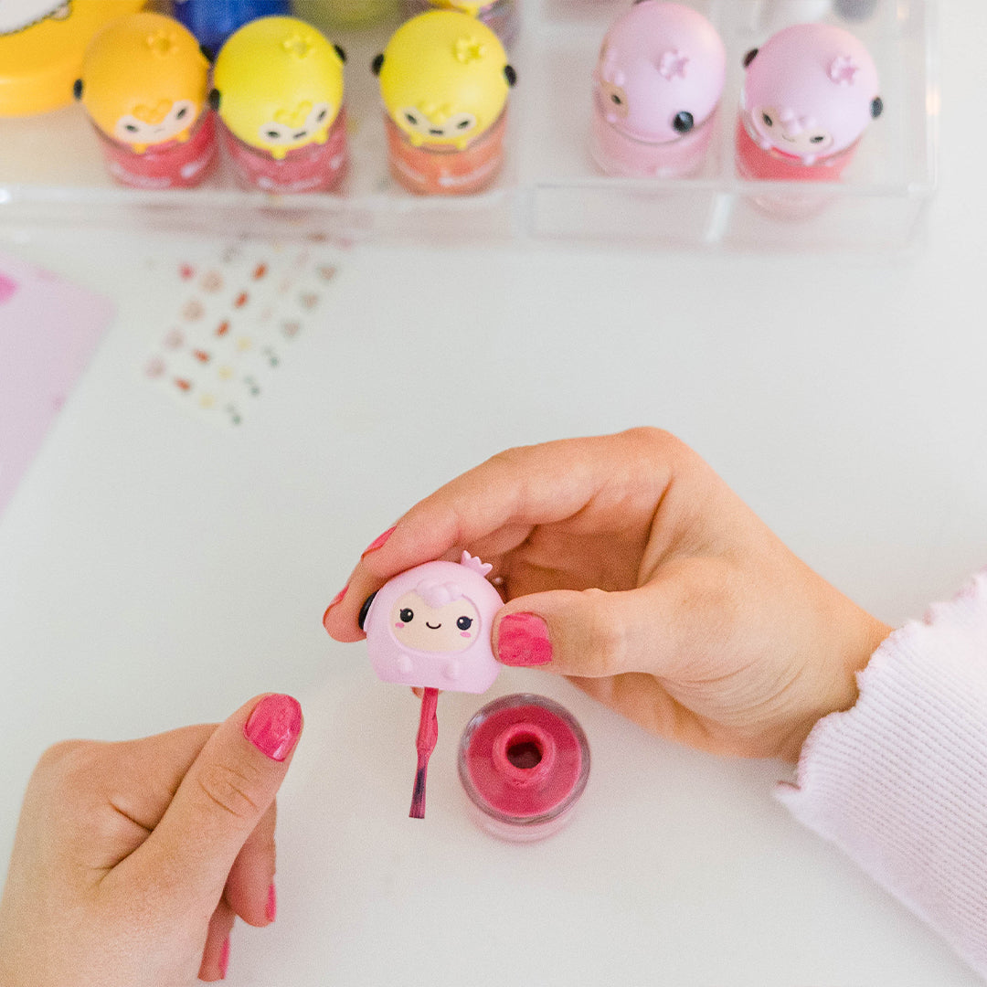 Woman painting nails with pink nail polish in a cute character bottle.