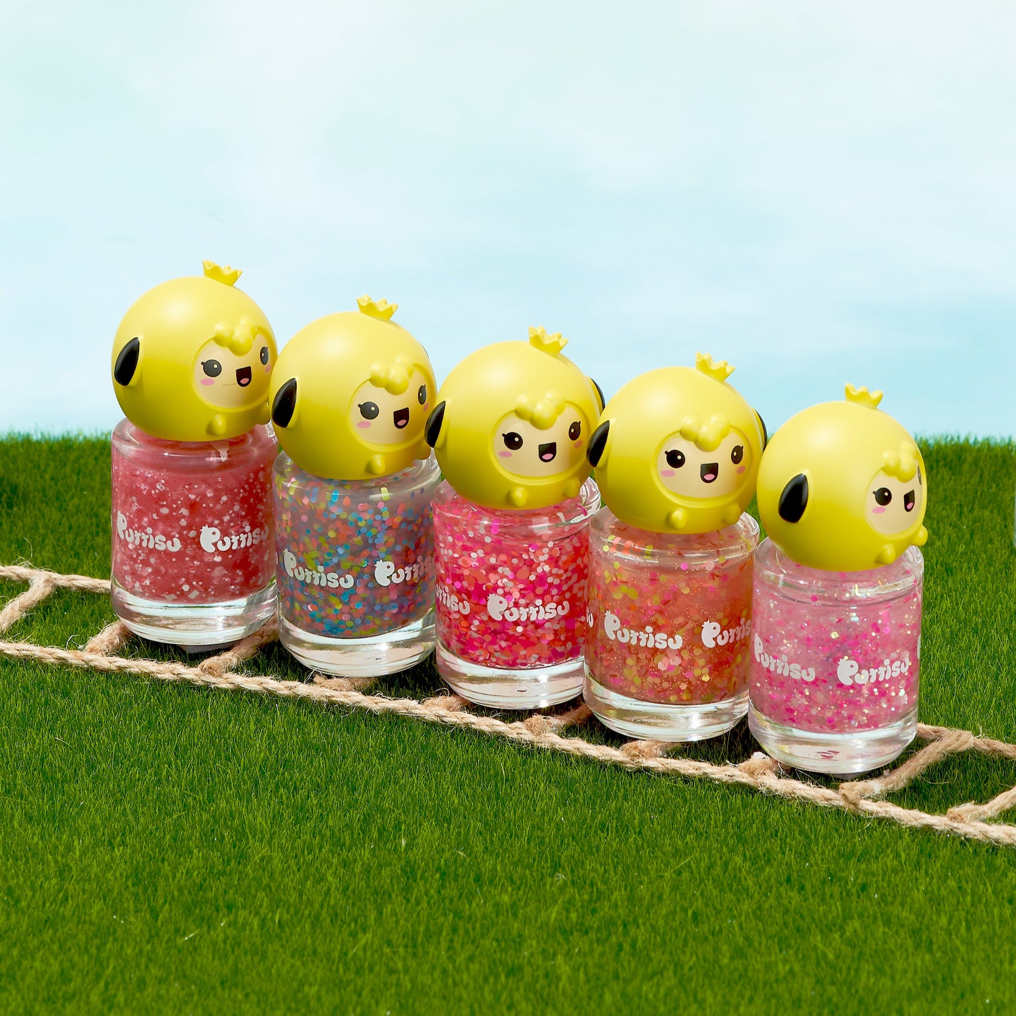 Five nail polish bottles with yellow chick-shaped lids on a grass and twine mat.