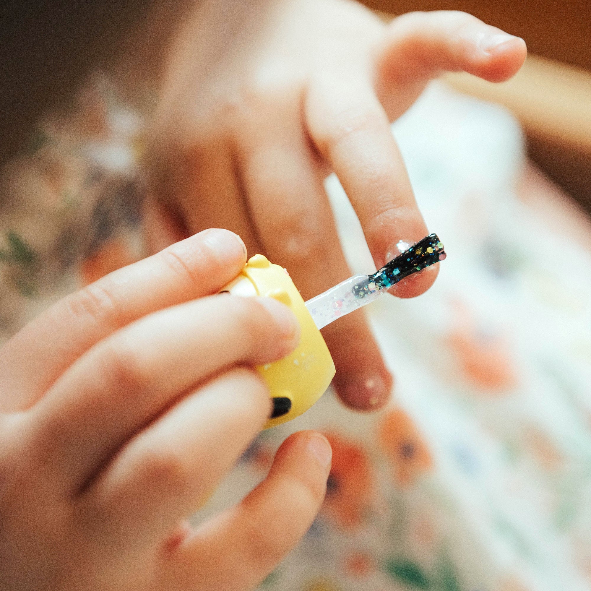Child applying glitter nail polish.