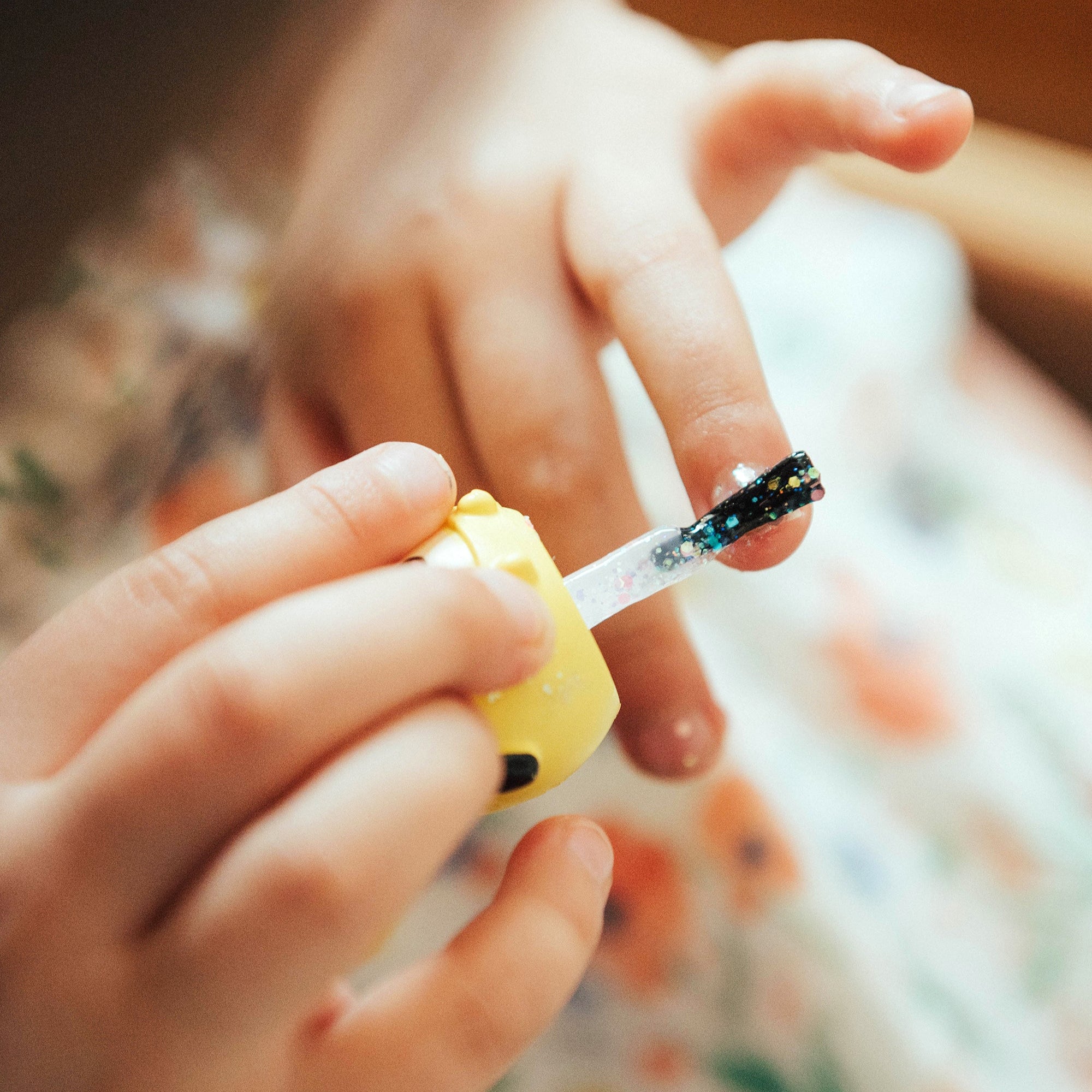 Child applying glitter nail polish.