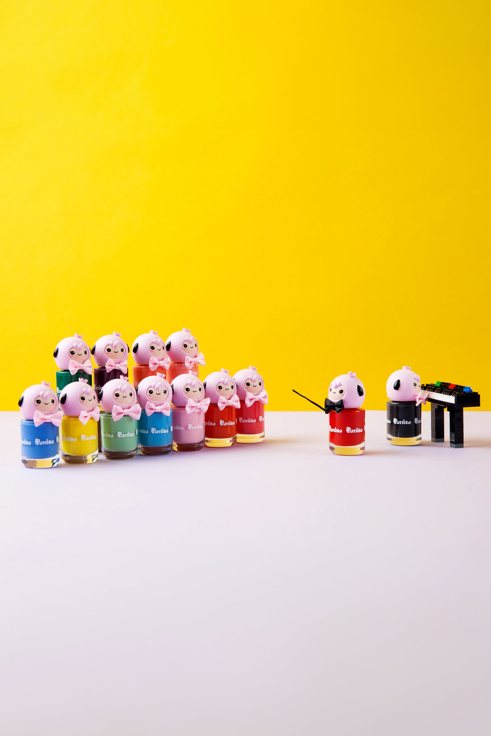 A collection of cartoon-character-topped nail polish bottles posed as a music class with a conductor and piano player.
