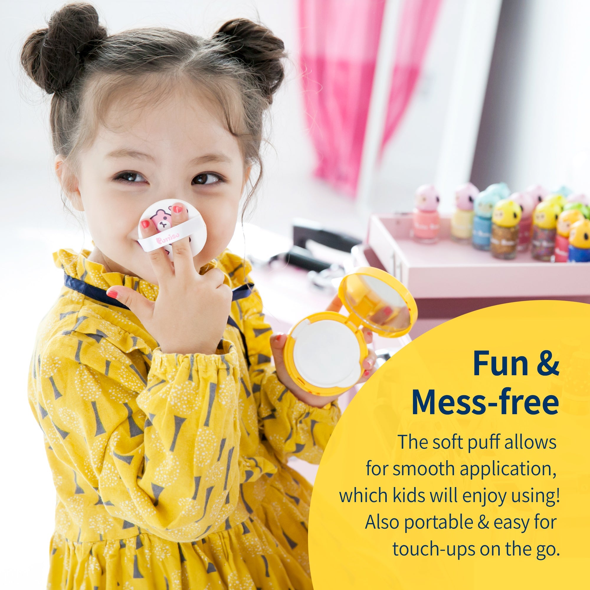 A young girl with two buns in her hair applies makeup with a yellow compact and white puff on her nose, wearing a patterned yellow dress in front of a pink vanity with nail polish bottles. A text overlay says, "Fun & Mess-free" with a product description.