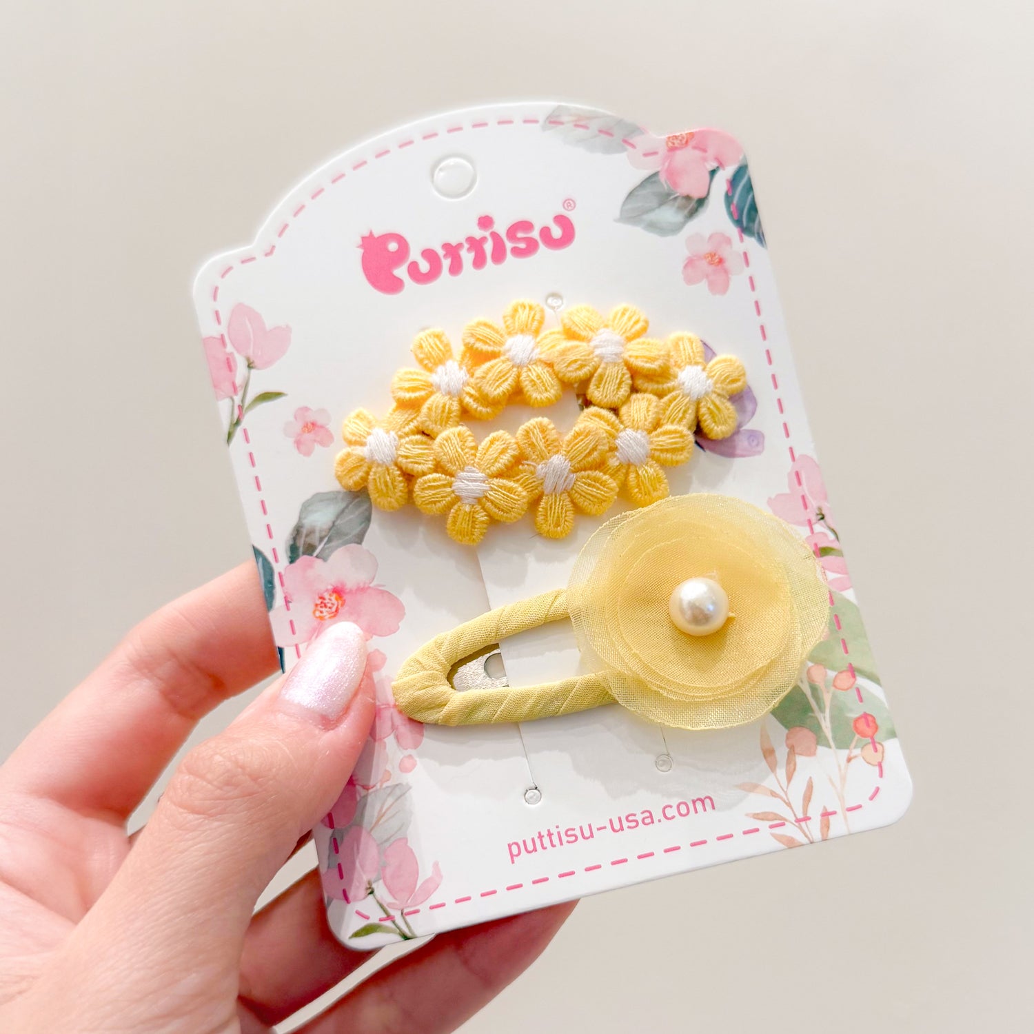 Two yellow flower hair clips on a floral card.