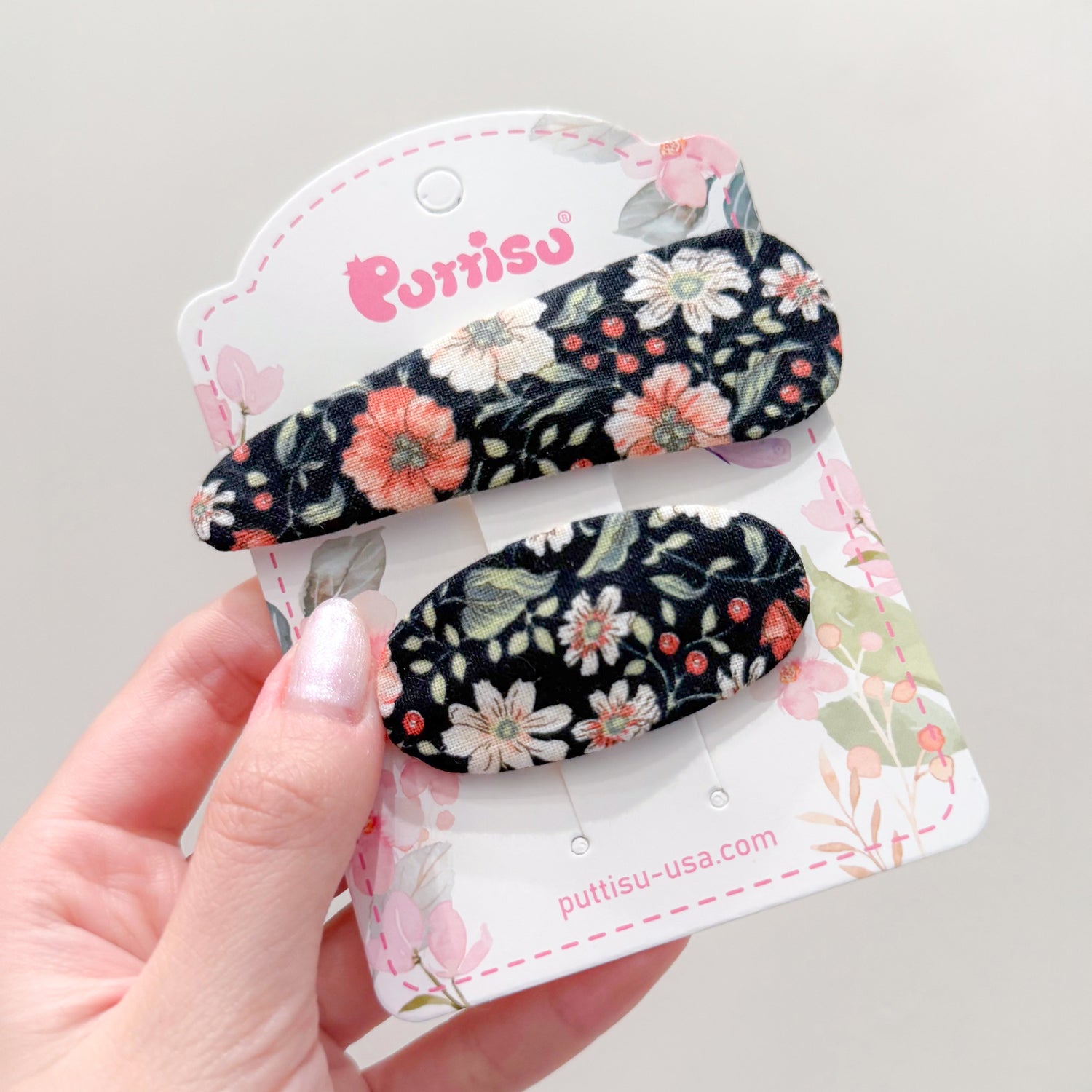 Two floral hair clips on a white card.