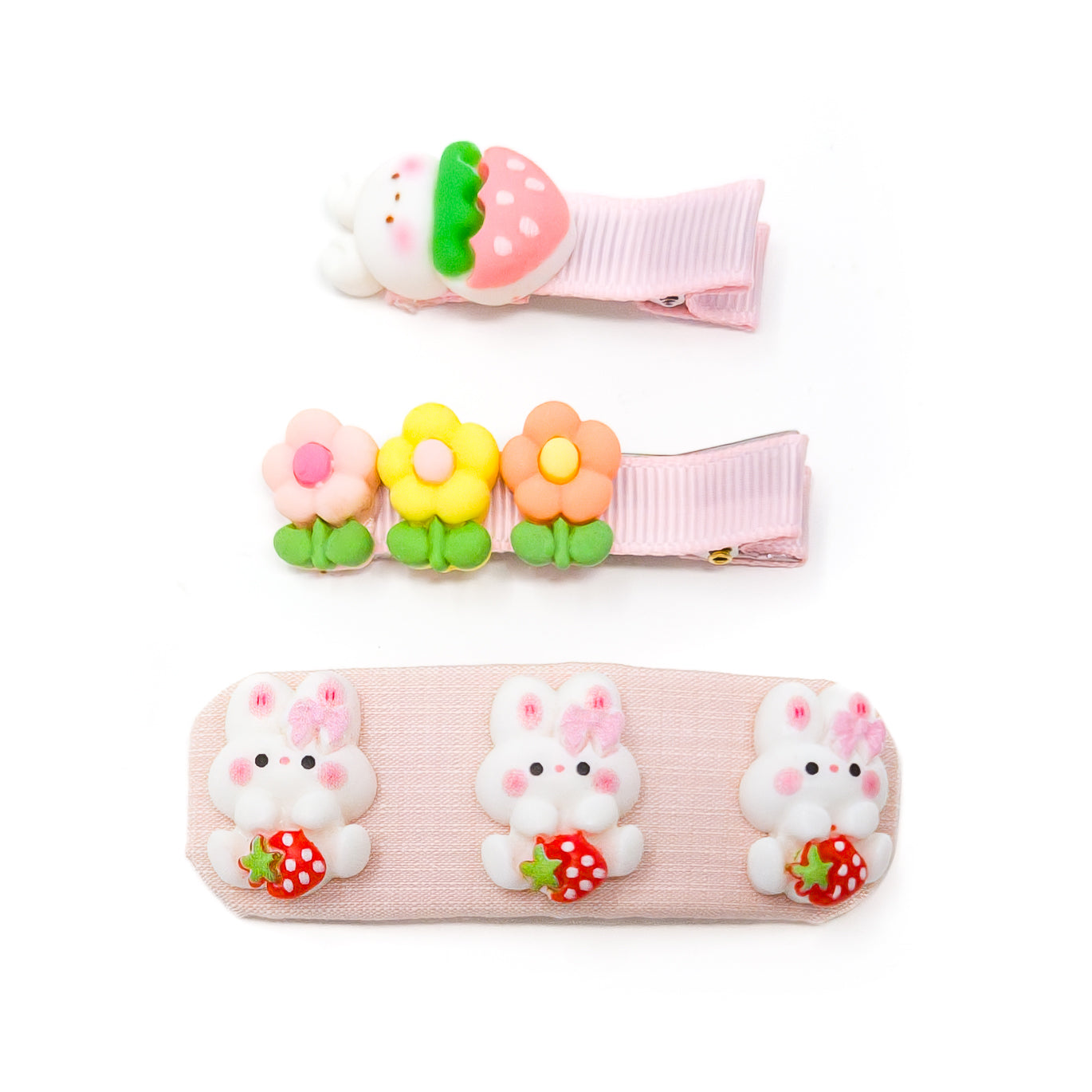 Three hair clips on a white background. The clips have a variety of designs, including strawberries, flowers, and rabbits.
