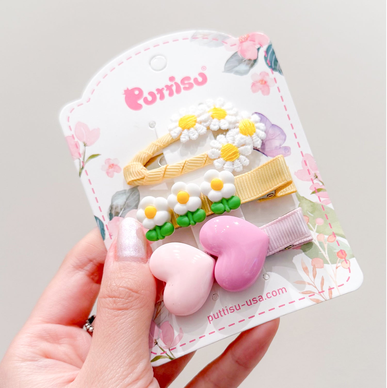 A hand holding a card with assorted colorful hair clips.