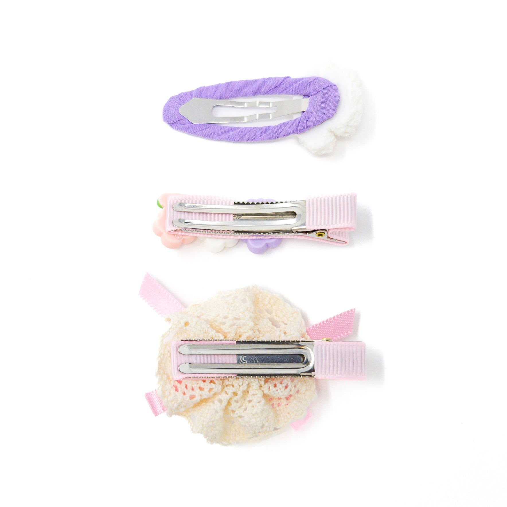 Three hair clips with various decorations, including a lavender fabric, small flowers, and lace with pink ribbons, are displayed on a white background.