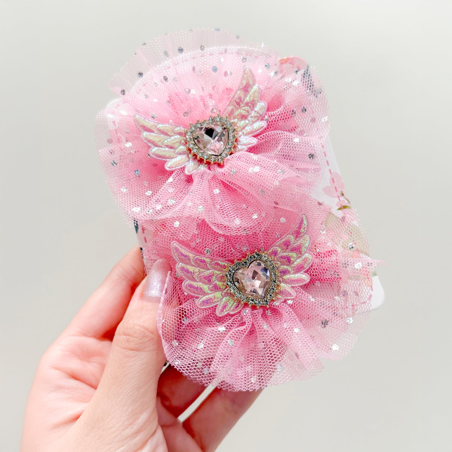 Pink hair clips with heart-shaped gems and wings.
