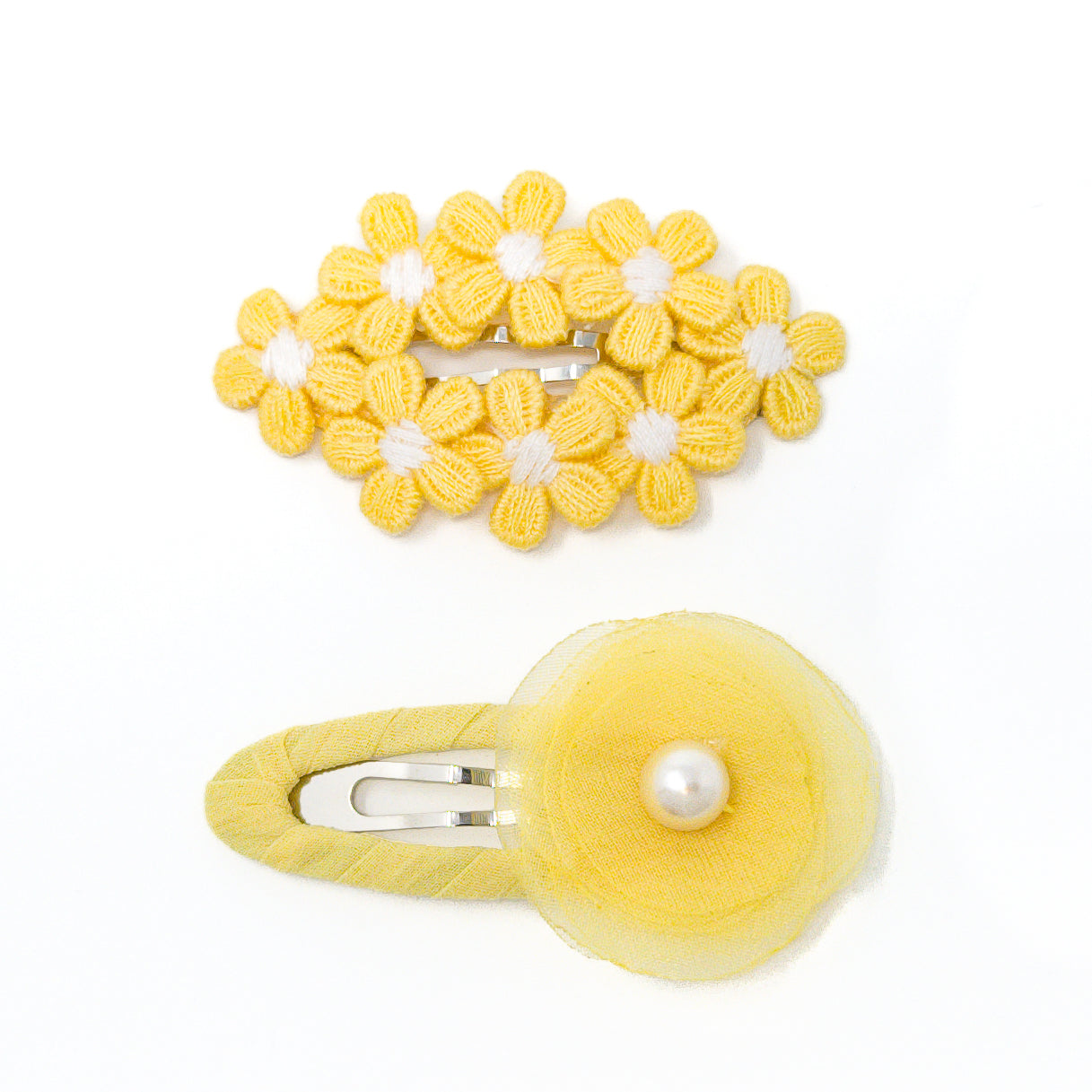 Two yellow hair clips with floral designs, one with multiple knitted flowers and the other with a sheer flower and pearl.