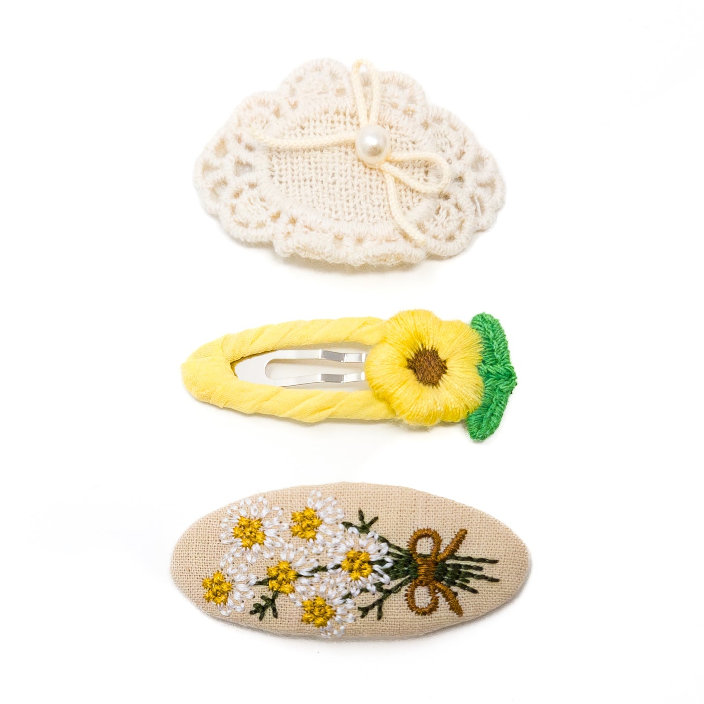 Three hair clips. Hand-crafted floral designs. White, yellow, and brown.