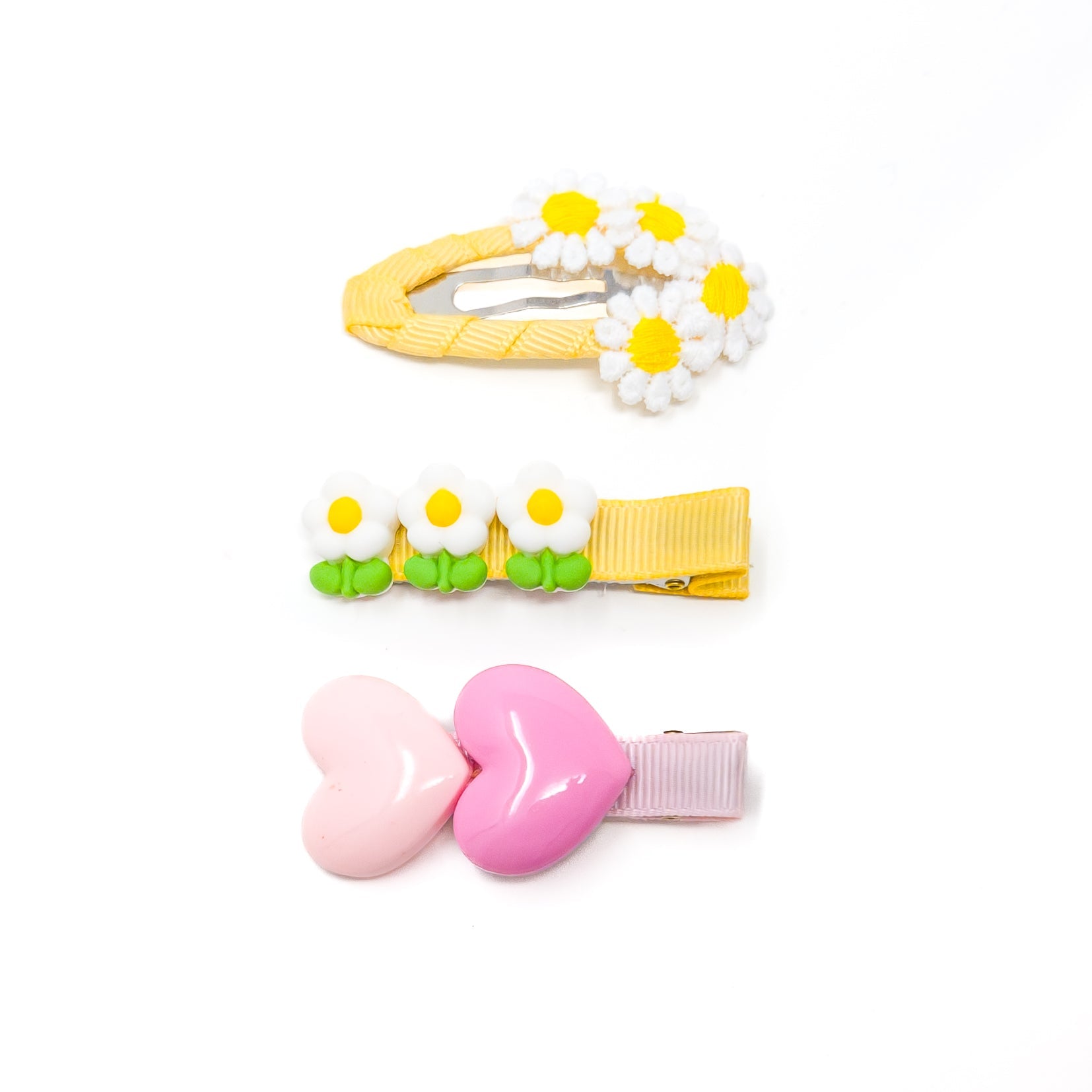 Three hair clips on a white background. The top clip has daisies, the middle clip has small white flowers, and the bottom clip has hearts.