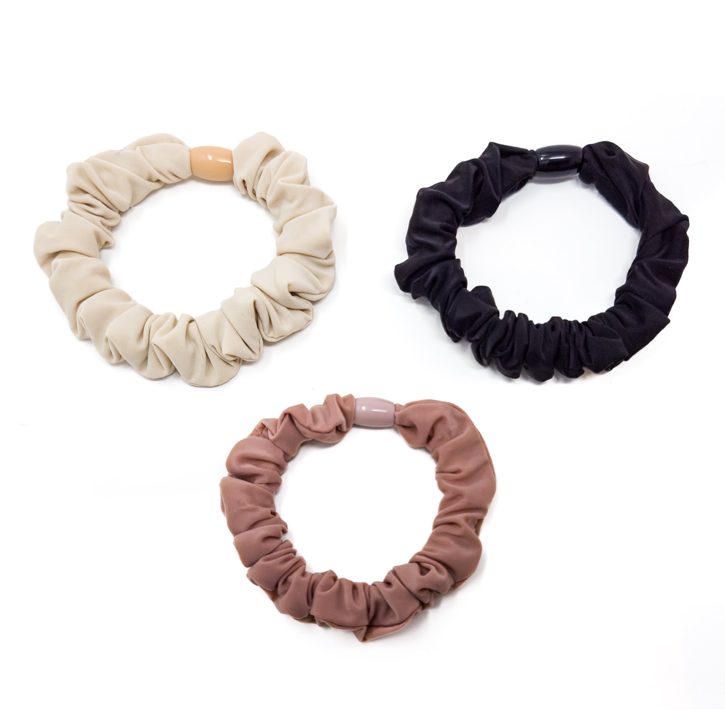 Three fabric hair ties with plastic connectors. One in beige, one in black, and one in rose brown.