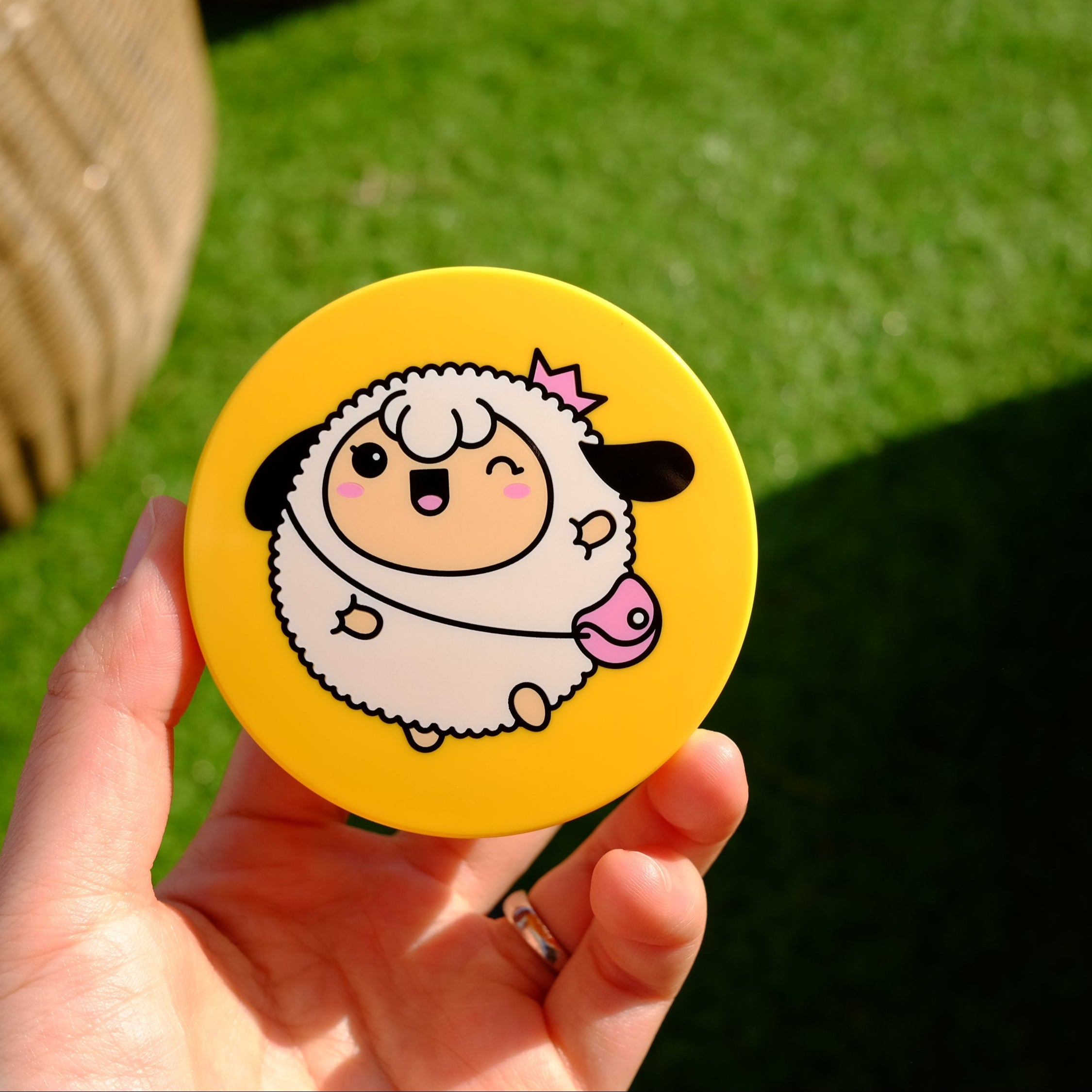 Hand holding yellow round container with cartoon sheep design.