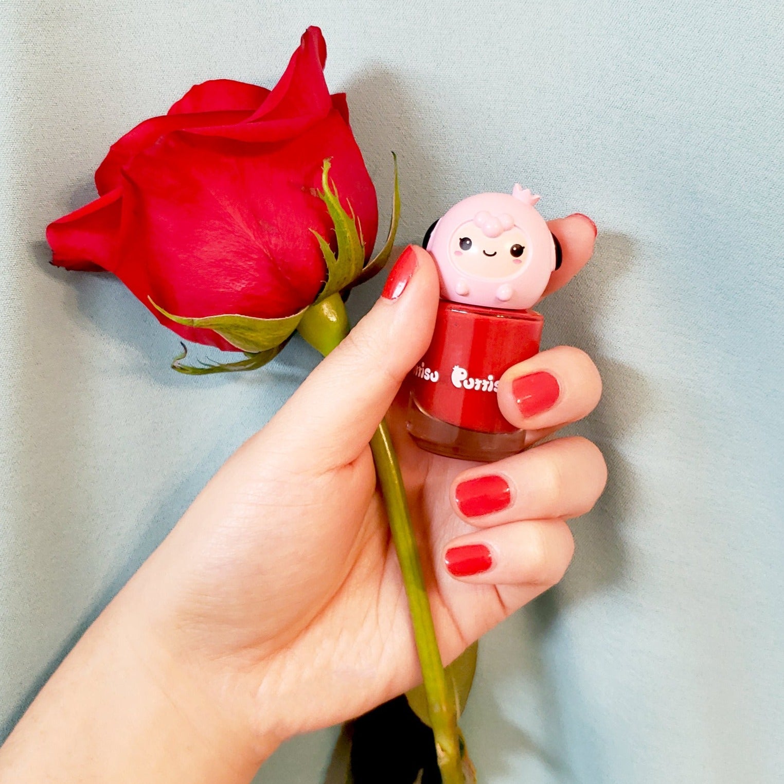 Hand holding red rose and red nail polish.