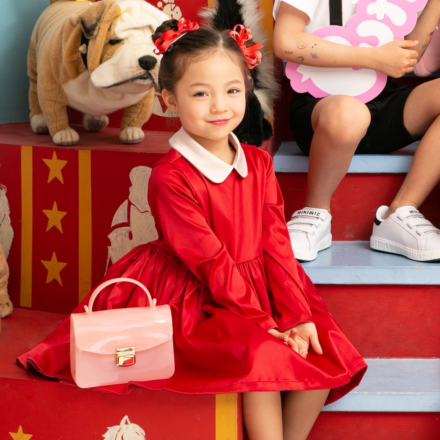 Girl in red dress, pink purse, red and white themed stage.