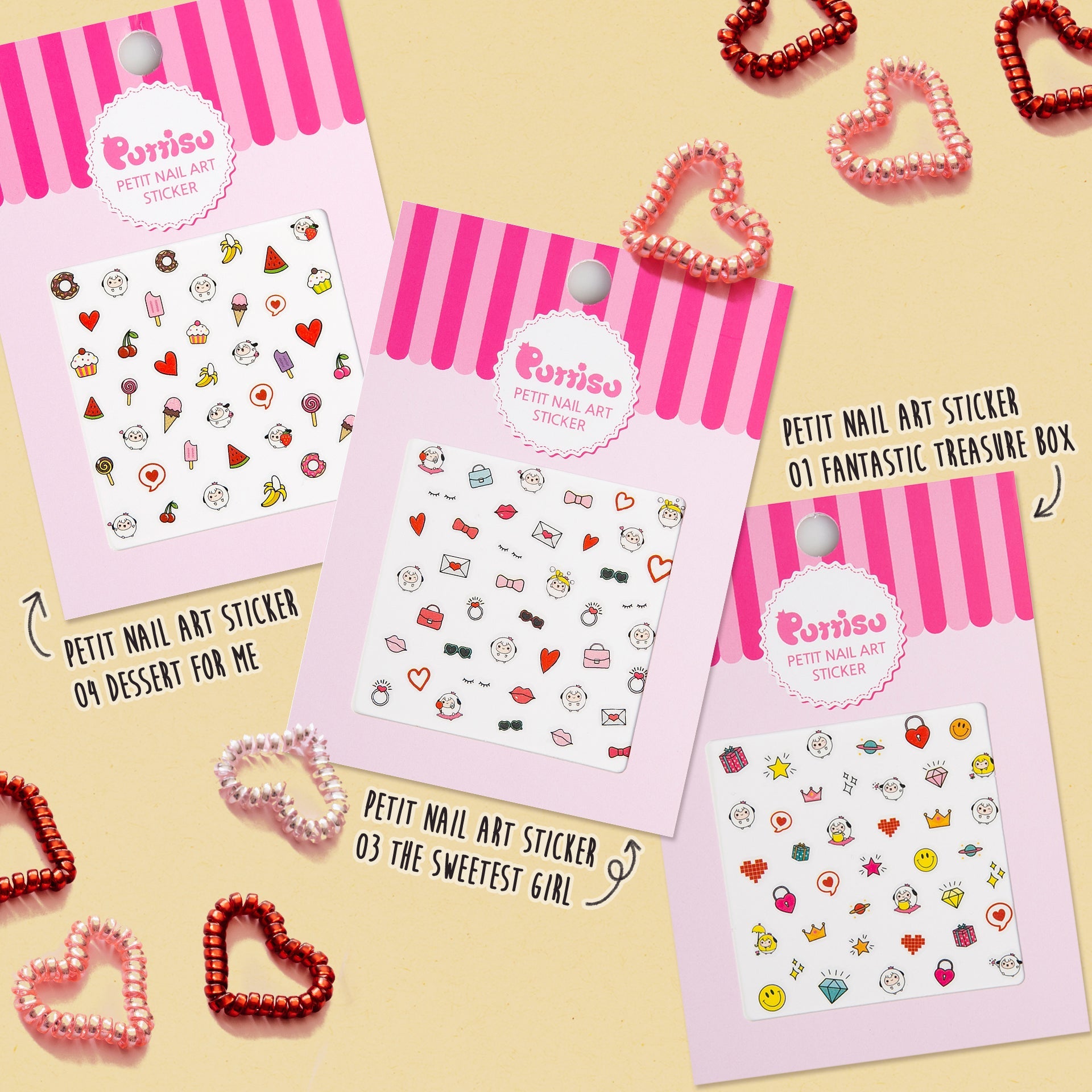 Three packages of Purriso nail art stickers with pink and white striped tops, arranged on a tan background alongside red and pink heart-shaped rings.
