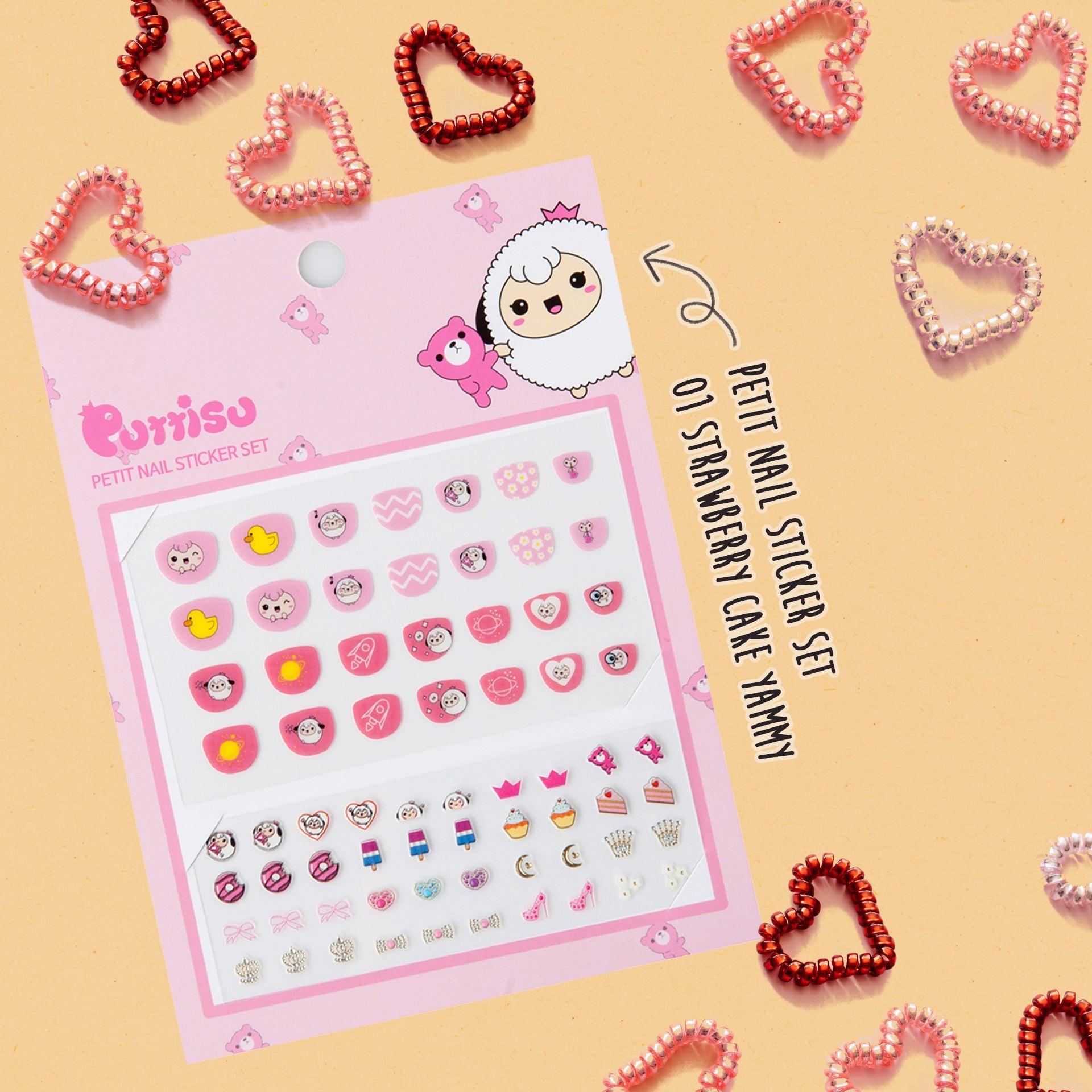 Pink and white "Purriso" Petit nail sticker set with cartoon sheep and food designs, surrounded by colorful spiral hair ties.