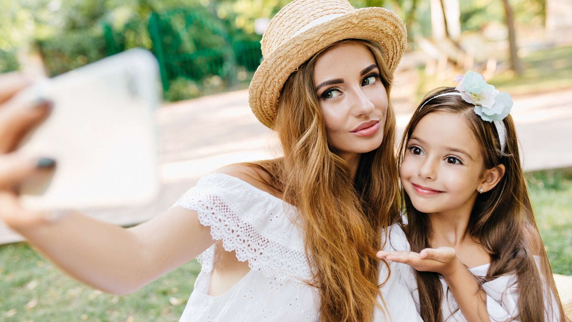 Mother and daughter taking a selfie together in the park on a sunny day