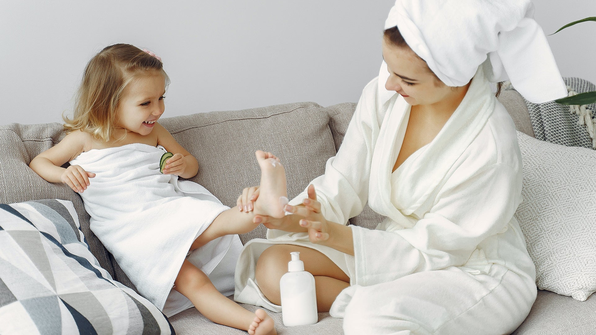 Mom and daughter enjoying skincare routine at home with lotion after bath.